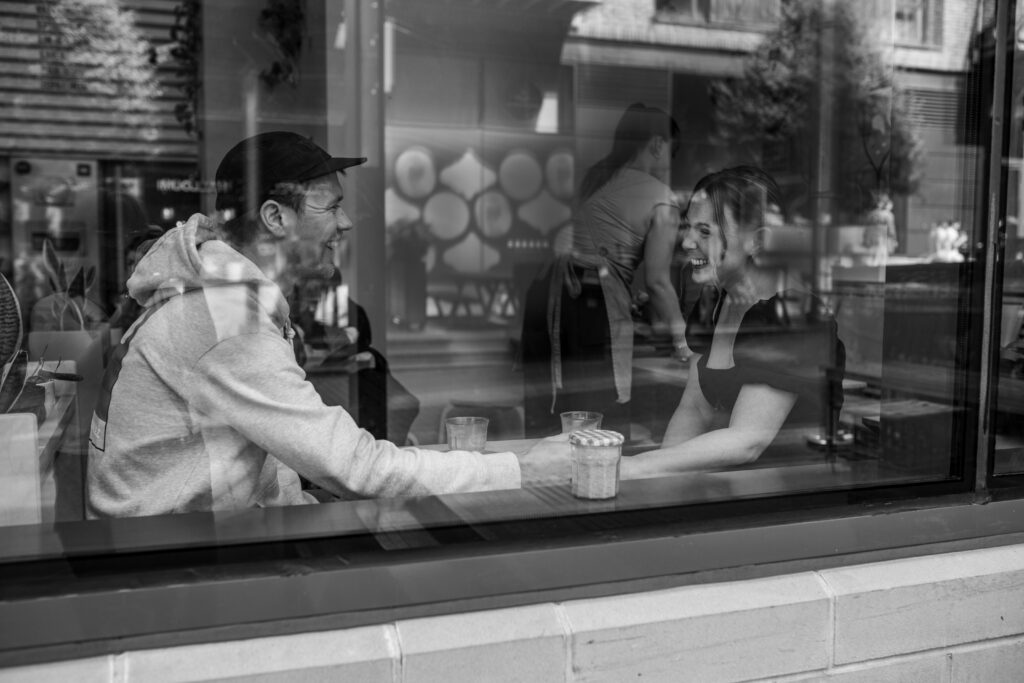a couple laughing and chatting during an engagement photoshoot in a cafe in bristol
