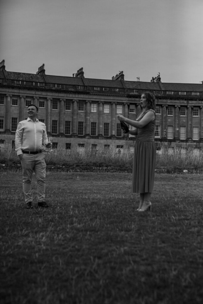 a couple popping champagne after a proposal in bath